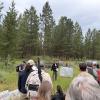 field tour group gathers in a meadow to listen to a presenter